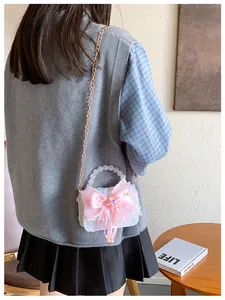 Détail du sac bleu pour fille avec nœud en soie rose, dentelle et poignée en perles