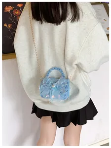 Détail du sac à main à paillettes bleu clair avec nœud en maille et perle ronde