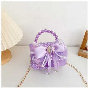 Détail du sac à paillettes violettes avec nœud en satin et poignée en perles
