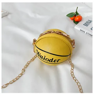 Detail of yellow basketball-shaped mini bag with PU leather texture and gold chain