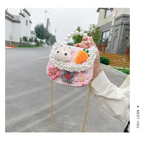 Close-up of pink tweed girl's handbag with pearl handle and plush rabbit decoration