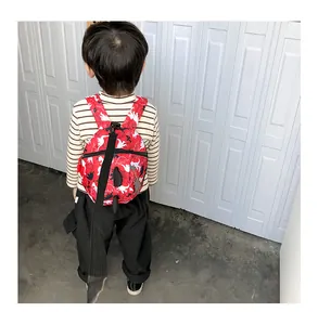 Detail of red toddler dinosaur backpack featuring long black safety leash for child security