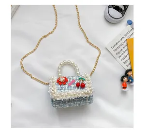 Détail du mini sac fille en tweed avec poignée en perles et écussons de cerises