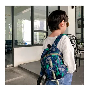 Close-up of children's navy backpack with green dinosaur prints and 3D spinal fin details