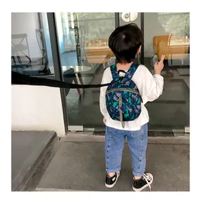 Close-up of a blue dinosaur toddler backpack with 3D spikes and safety leash attached