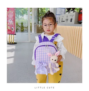 Detail of purple plaid children backpack with cute plush rabbit charm and fashion logo