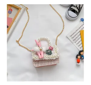 Détail du sac fille en tweed rose avec poignée en perles, breloque lapin et chaîne dorée