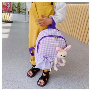 Detail of purple checkered kids backpack featuring a cute bunny plush and fashion patch