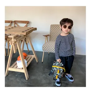 Toddler modeling a striped long sleeve shirt with a camouflage dinosaur backpack