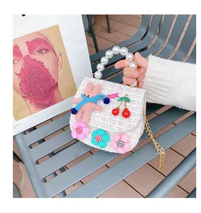 Detail of tweed children bag with knit rabbit, cherry decor and pearl handle