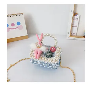 Détail d'un sac en tweed pour fille avec poignée en perles et lapin en peluche