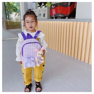 Detail of purple checkered kids backpack with cute bunny plush pendant and matching drawstring bag