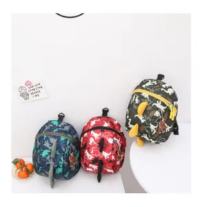 Three dinosaur backpacks with 3D scales in red, navy, and green for toddlers