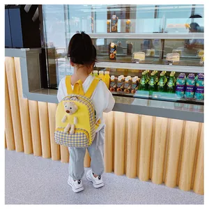 Detail of yellow canvas backpack for kids featuring a plush bear and purple plaid pattern