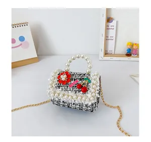 Détail d'un sac à main en tweed noir et blanc pour fille avec poignée en perles et broderie