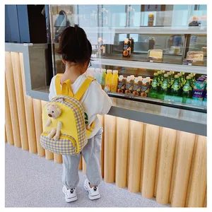 Detail of yellow toddler backpack with a plush bear and plaid patterns on kid model