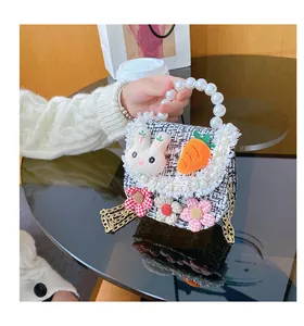 Close-up of girl's tweed crossbody bag with pearl handle and plush rabbit decor