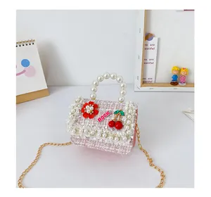 Détail du mini sac fille en tweed rose avec poignée en perles et breloque cerise