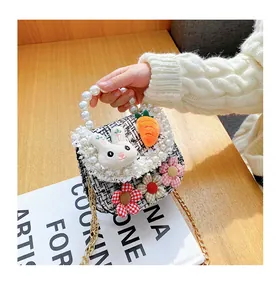 Close-up of kids tweed crossbody bag with pearl handle, plush bunny and floral charms