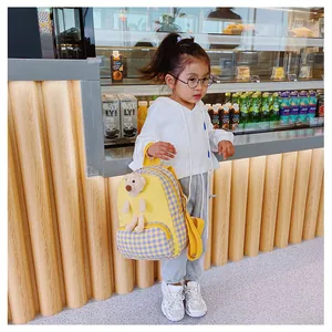 Detail of yellow and plaid kids backpack with a 3D plush bear on a soft fabric finish