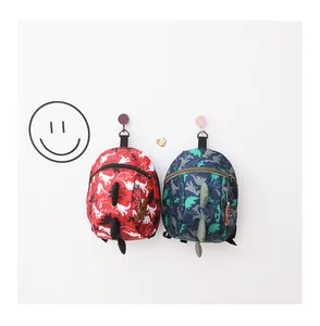 Detail of cartoon dinosaur backpacks with 3D fins in red and navy for toddlers