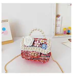 Detail of red tweed girl handbag with pearl handle, floral decor, and gold chain strap