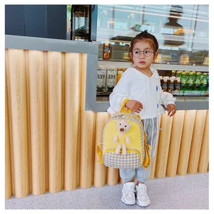 Detail of yellow toddler backpack with 3D teddy bear and blue gingham pattern accents