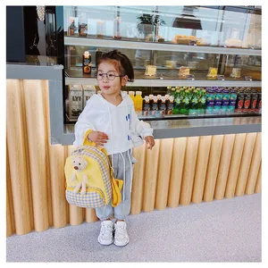 Detail of yellow plaid toddler backpack featuring a 3D plush bear on the front pocket