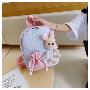 Detail of pink and blue plaid kids backpack featuring a plush bunny and drawstring pocket