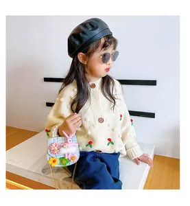 Detail of woven kids crossbody bag with crochet flowers and plush bunny on a girl