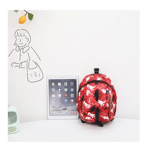 Detailed view of mini red dinosaur backpack for kids next to an iPad for size comparison