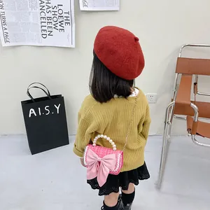 Girl's pink tweed crossbody bag with bow, pearl handle, and gold chain strap