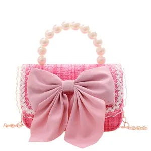 Pink tweed crossbody bag for girls with pearl handle and bow decoration on white background
