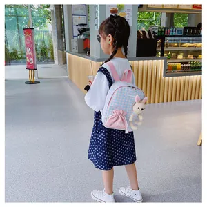 Detailed shot of pink and blue plaid toddler backpack featuring a white plush bunny charm