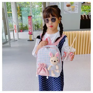 Close-up of cute rabbit plush on checkered toddler backpack in a cafe setting