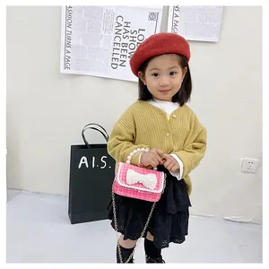 Pink tweed girls crossbody bag with pearl handle and white bow detail on young model