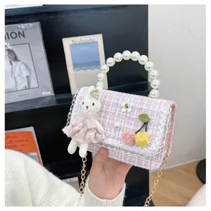 Détail de la poignée en perles et lapin en peluche sur sac à carreaux rose enfant