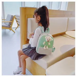 Toddler backpack with plush bear detail worn by a child in a bright room