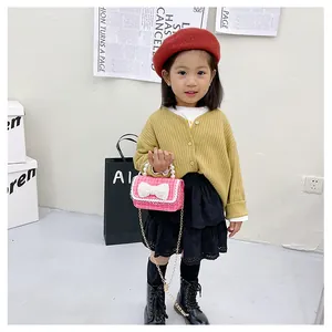 Pink tweed girl's mini handbag featuring white pearl bow and golden chain strap
