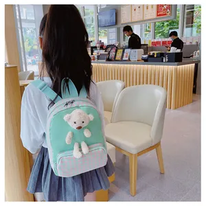 Rear view of a green kids backpack with checkered pockets and a plush bear toy