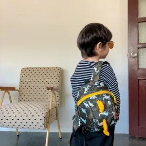 Kids dinosaur camouflage backpack with yellow fins shown on a child for school