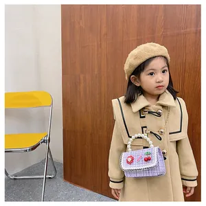Girl in tan coat wearing purple tweed handbag with pearl handle and gold chain strap