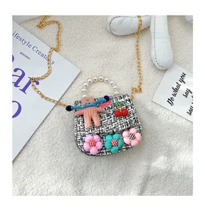 Detail of tweed girl's mini bag featuring pearl handle and cute rabbit pendant charm