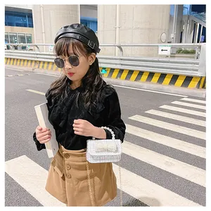 Detail of girls tweed crossbody bag with pearl handle and bow accent in street style