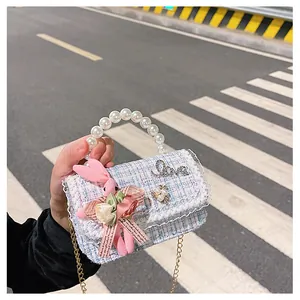 Détail d'un sac en tweed pour enfant avec poignée en perles et charme lapin en peluche