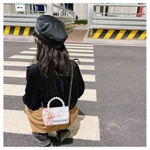 Détail du mini sac à carreaux bleus avec poignée en perles et breloque lapin rose en rue
