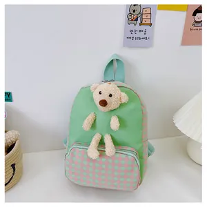Detail of cute green rabbit toddler backpack featuring a 3D plush teddy bear ornament