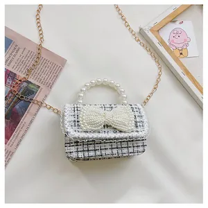 Detail of tweed check kids bag featuring oversized pearl bow and pearl bead handle