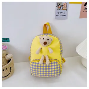 Close-up of cute 3D plush bear on yellow canvas and plaid fabric children's backpack