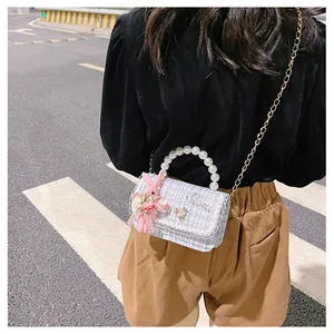 Détail de la texture en tweed, poignée en perles et lapin en peluche sur ce sac de fille